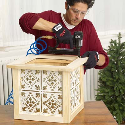 Man adding the top cap to the Christmas tree box.