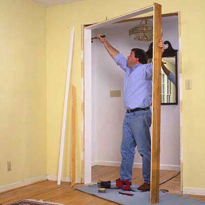 A man removes jambs and molding as a part of the process of creating an archway out of a doorway.