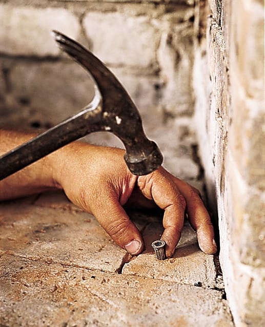 A man inserts lead anchors for screws.