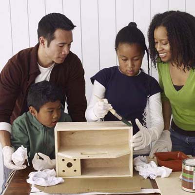 A family applies stain to a toolbox.