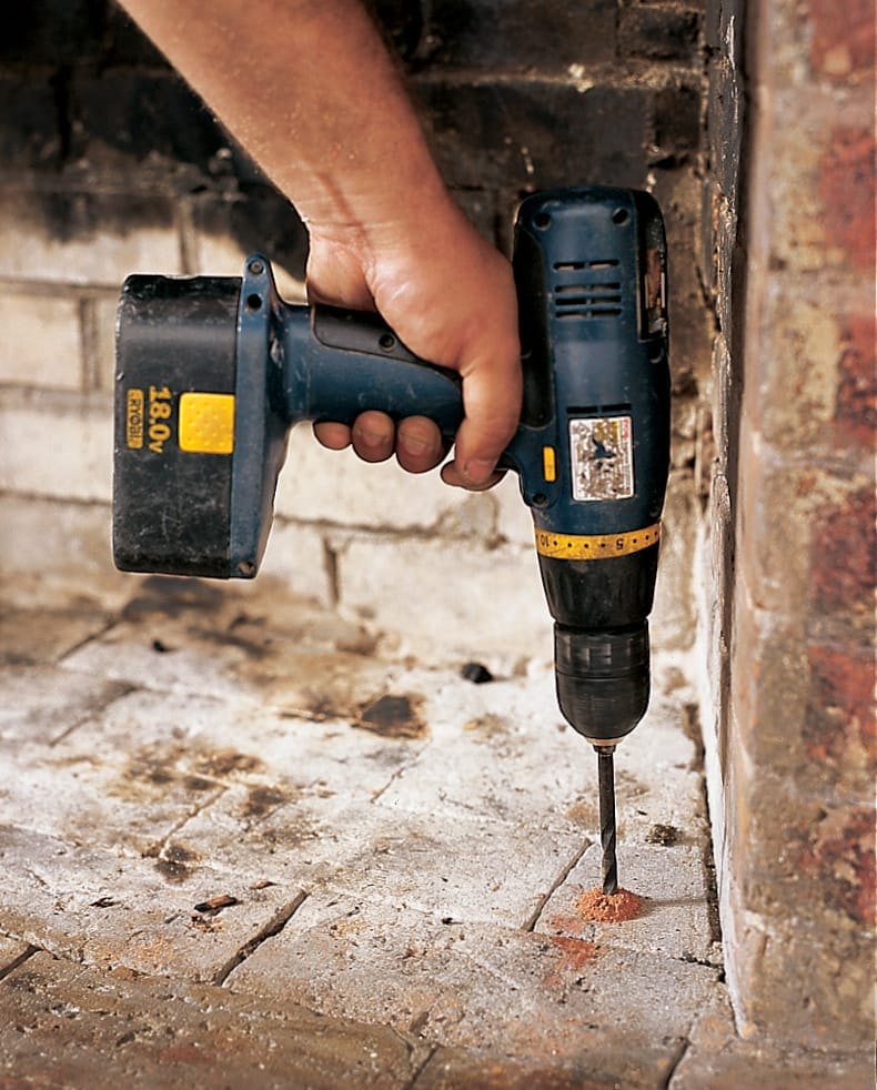 A man drills holes for lead anchors.