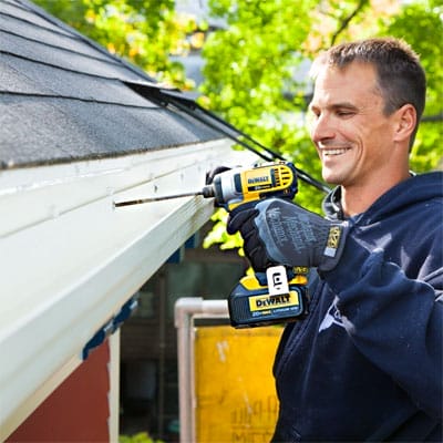 A man using a drill to install a fiberglass gutter.