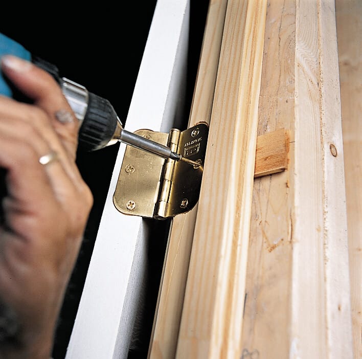 Photo of Tom Silva replacing the hinge screw of a prehung door. 