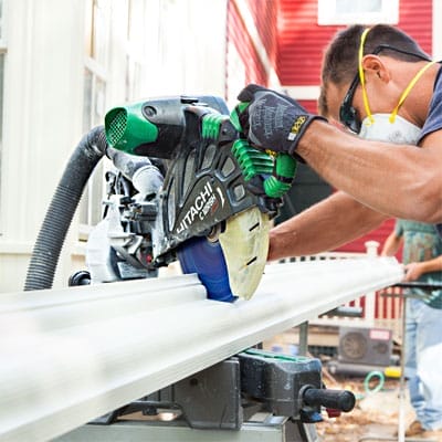 A man using a saw to cut a fiberglass gutter.