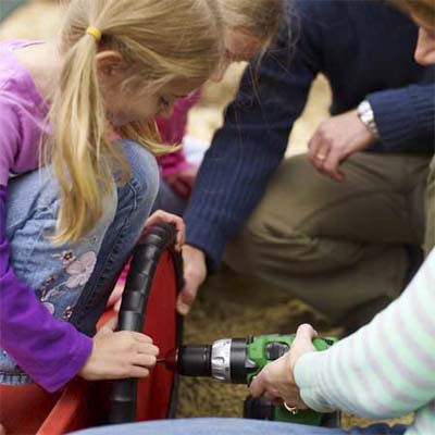 Man drilling the steering wheel onto the sandbox