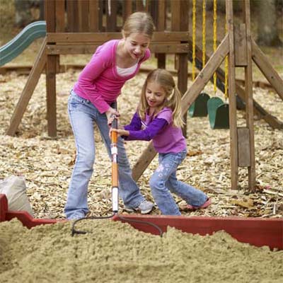 Young girls adding sand to the sandbox
