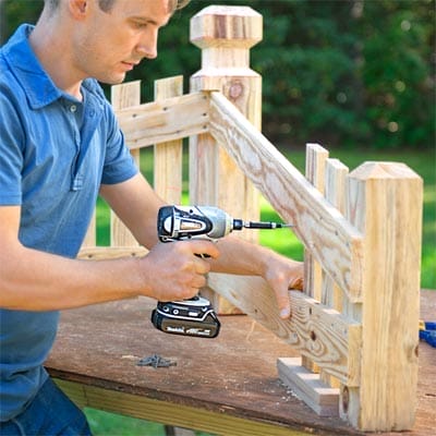 A drill being used to connect the wooden balusters to a driveway marker.