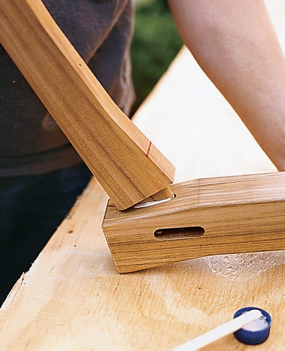 Craftsman inserting glued tenon into mortise slot during swing assembly.
