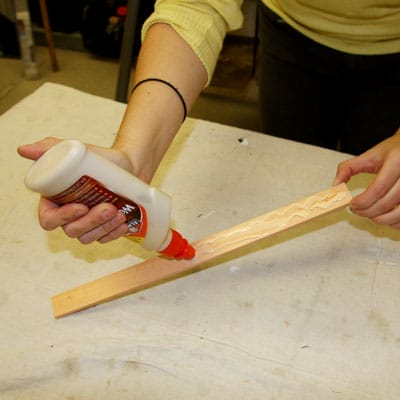 A person applying glue to a piece of table trimming