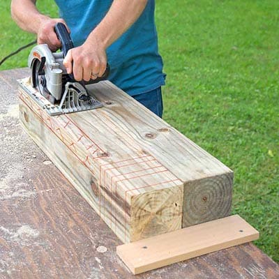 A circular saw being used to cut through a wooden post for a driveway marker.