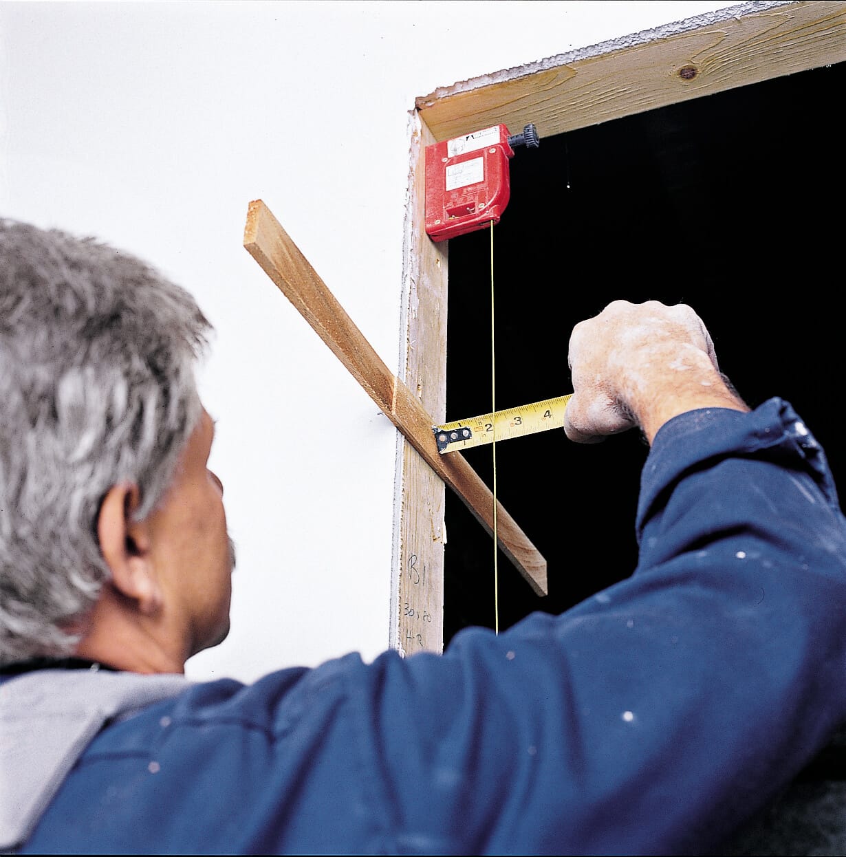 Photo of Tom Silva shimming the trimmers as a part of the prehung door installation process. 