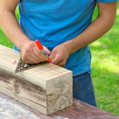 A plank of wood being marked by a red sharpie.