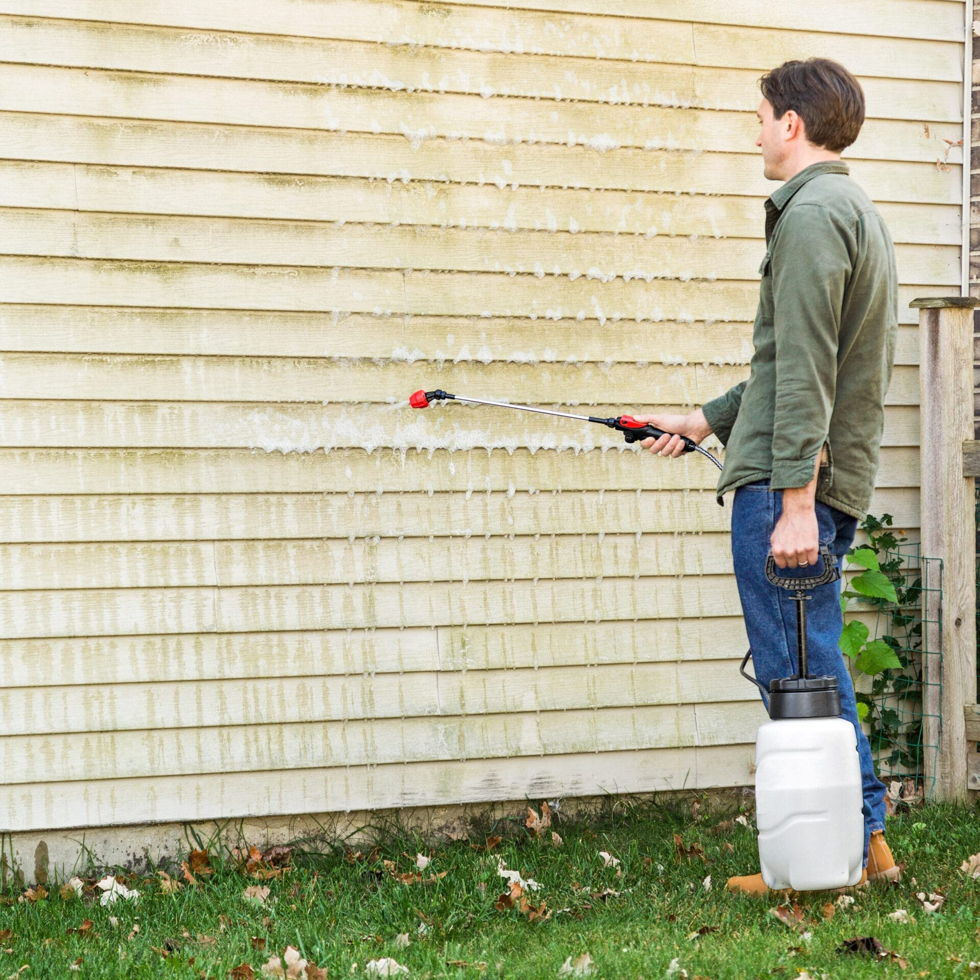A man powerwashing a wall with mildew on it.
