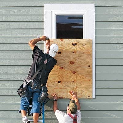 Two men boarding up a window.