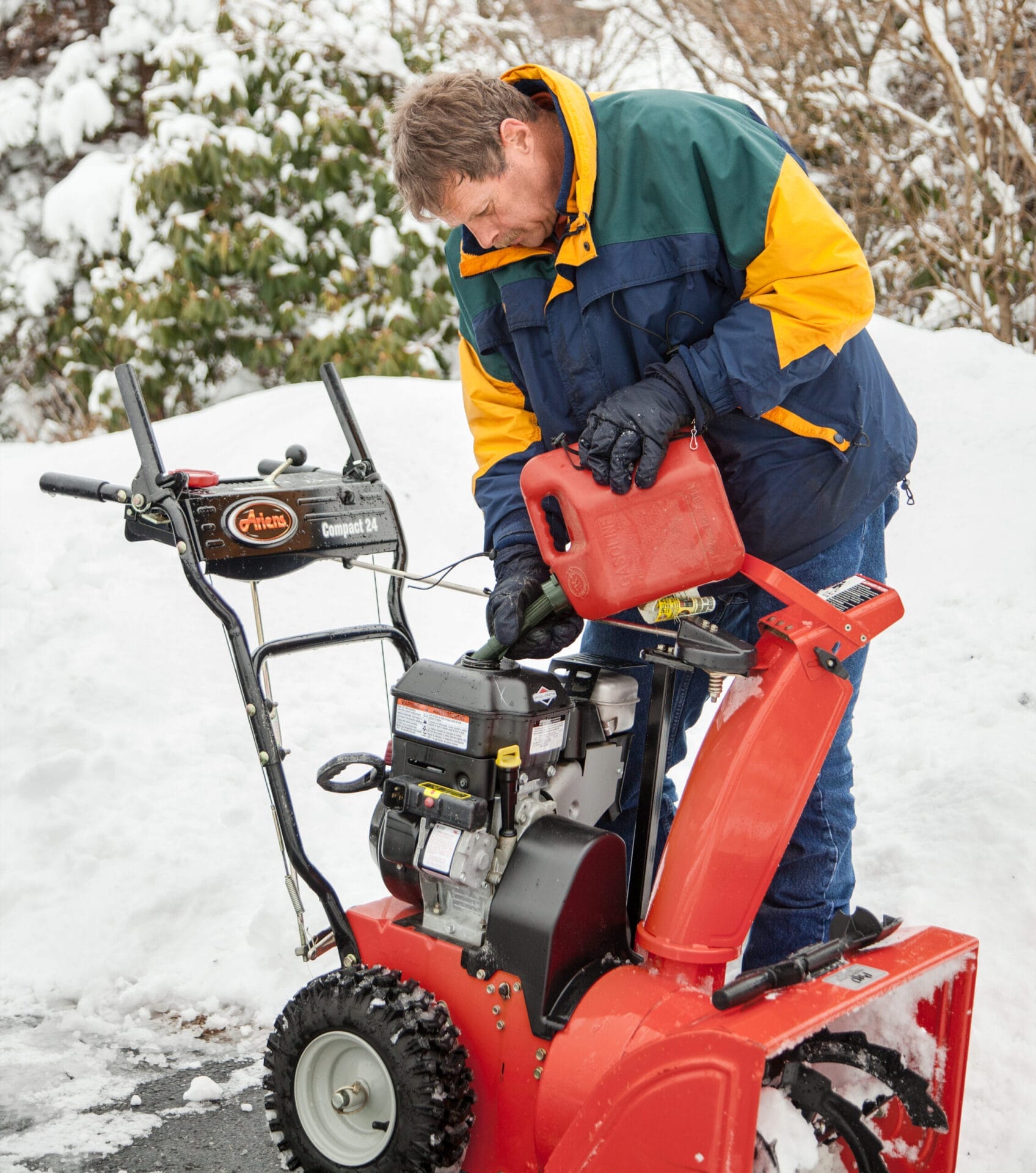 A man putting gas into a snowblower.