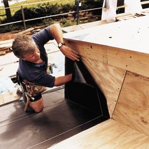 A man applying a waterproof membrane to a wooden surface.