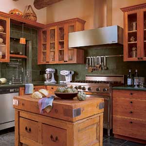 The kitchen's stainless steel range and exhaust hood are flanked by custom cherry cabinets. Black slate covers the countertops, backsplash, and floor.