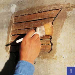 A coat of plaster being applied to a wall with a brush.