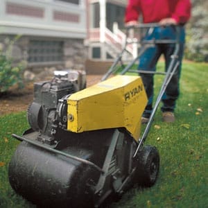 Pushing a gas-powered aerator.