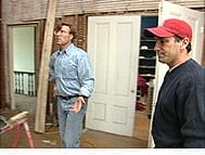 Two men discuss renovation in a house.