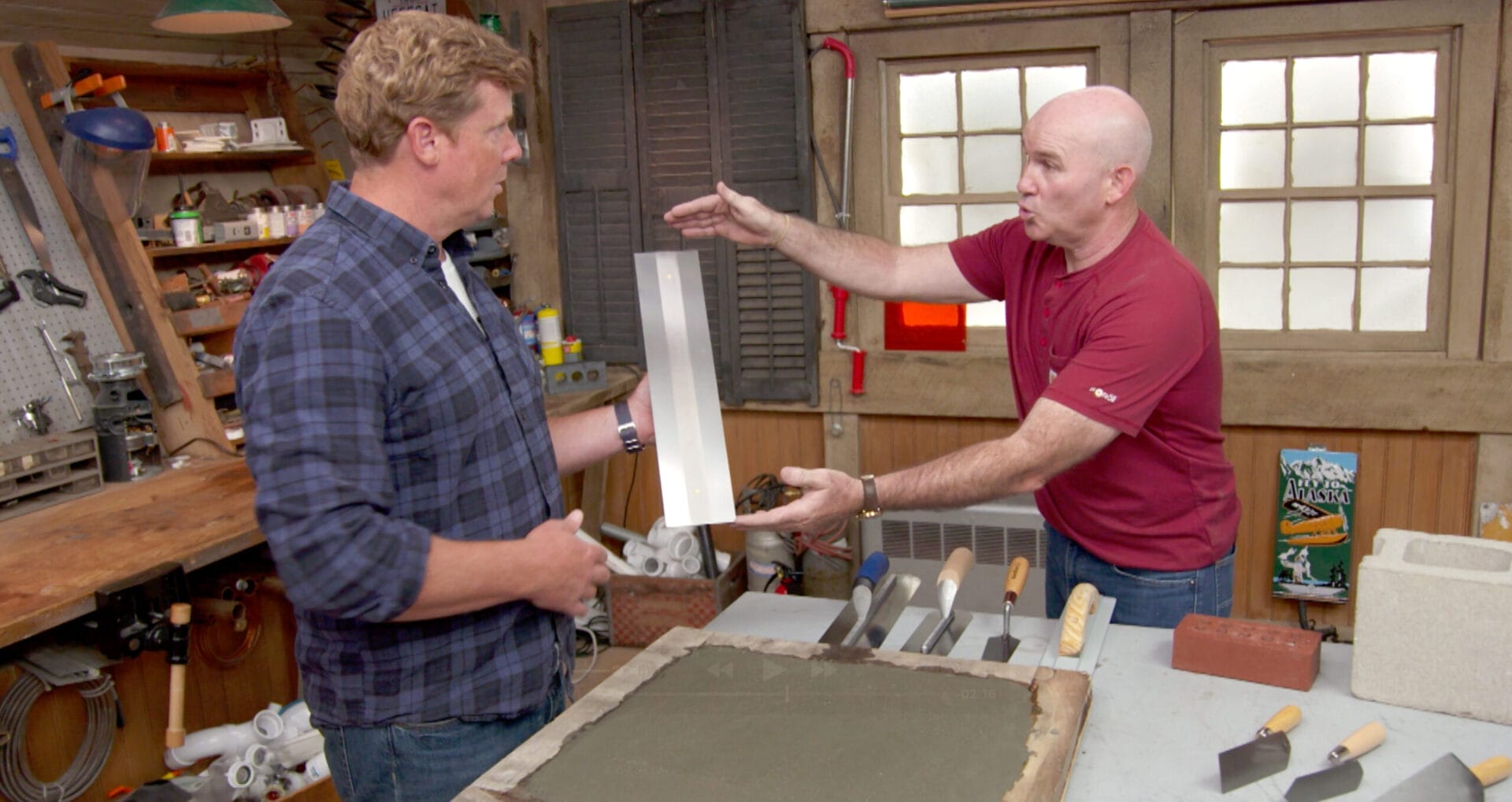 Two men talking while the one on the left holds a masonry trowel.