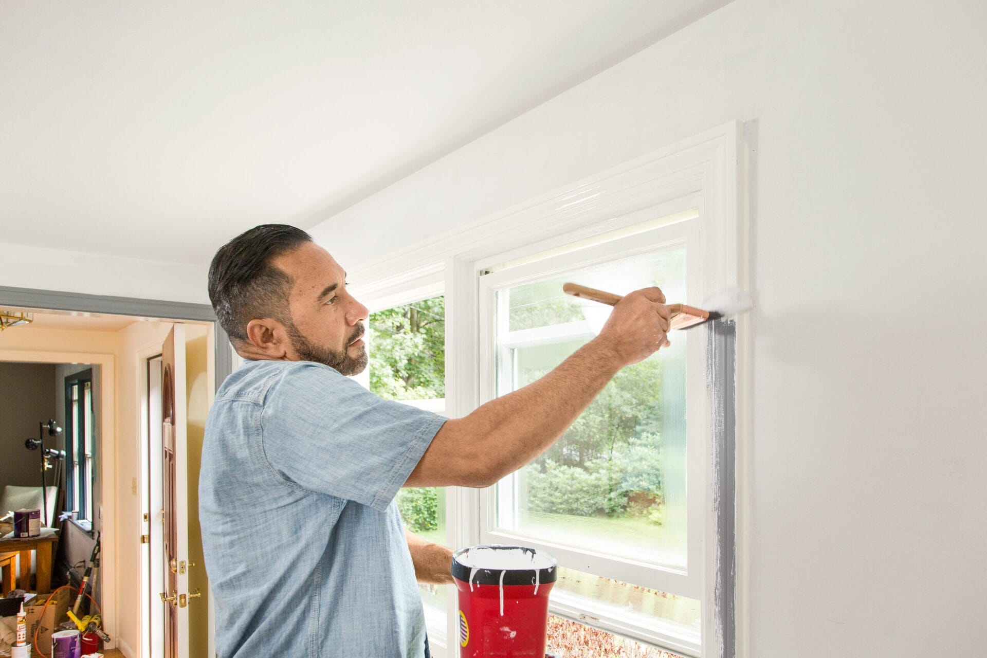 A man painting the edges of a window.