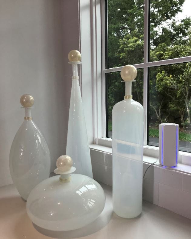 Small white air quality monitoring device next to decorative vases.