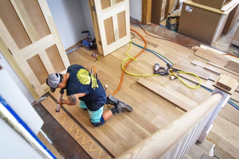 Jonathan Gramajo of GQ Hardwood Floors installing random-width white oak boards in entry area.