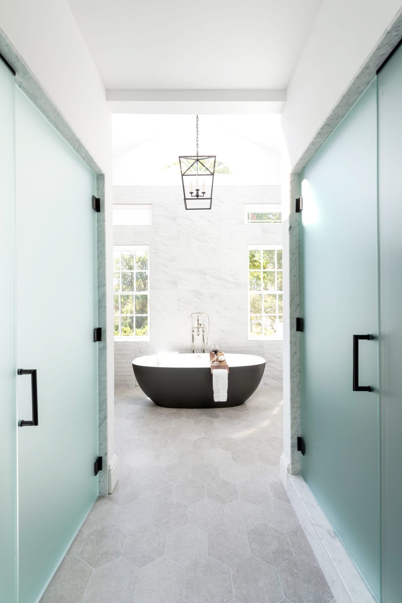 A view of the bathtub with a large pendant light hanging above.
