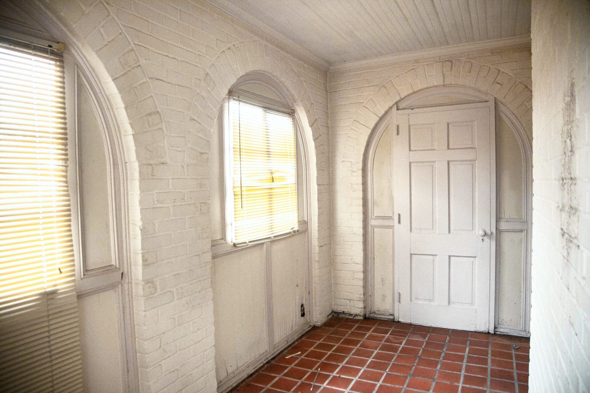 A sunroom with several arched openings around windows and the door.
