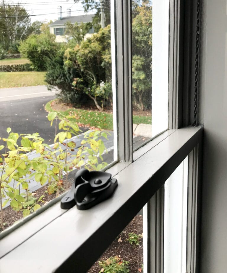 A restored double-hung window with brass hardware including historically accurate sash pulleys, chains, and window locks.