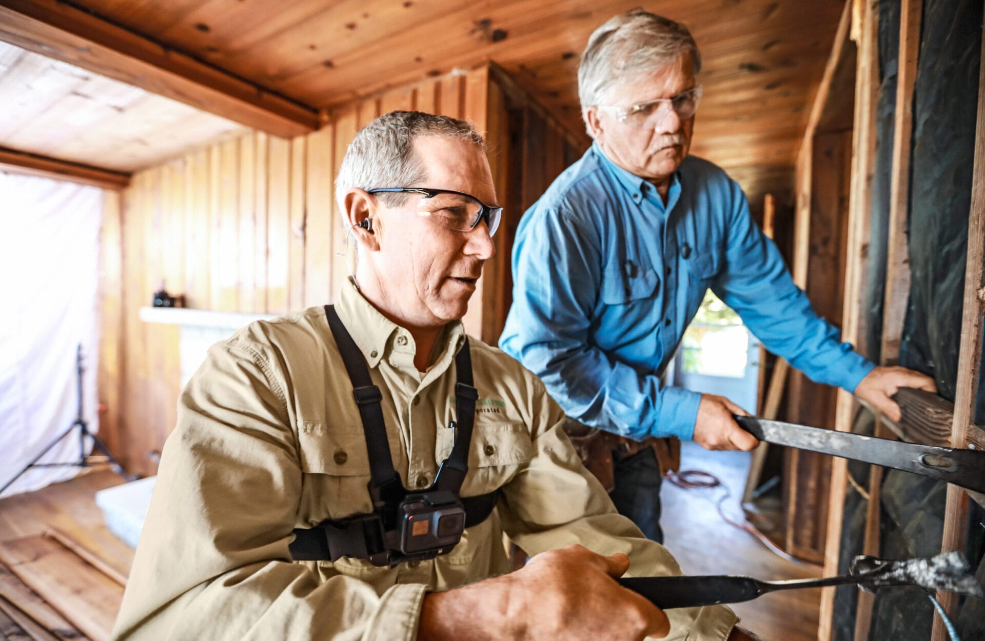 Jeff Sweenor and Tom Silva carefully removing knotty pine paneling from interior walls for reuse in playroom renovation.