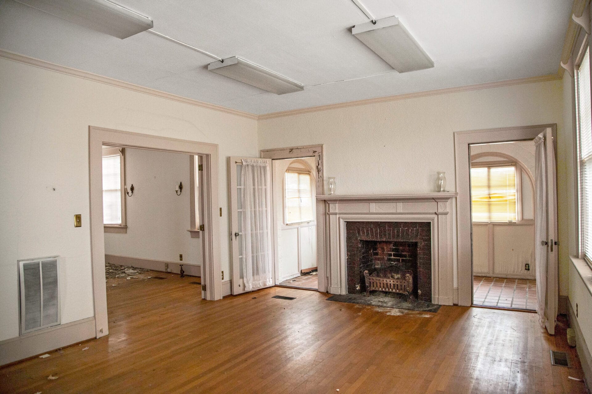 An empty living room with original wood floors and a colonial mantel.