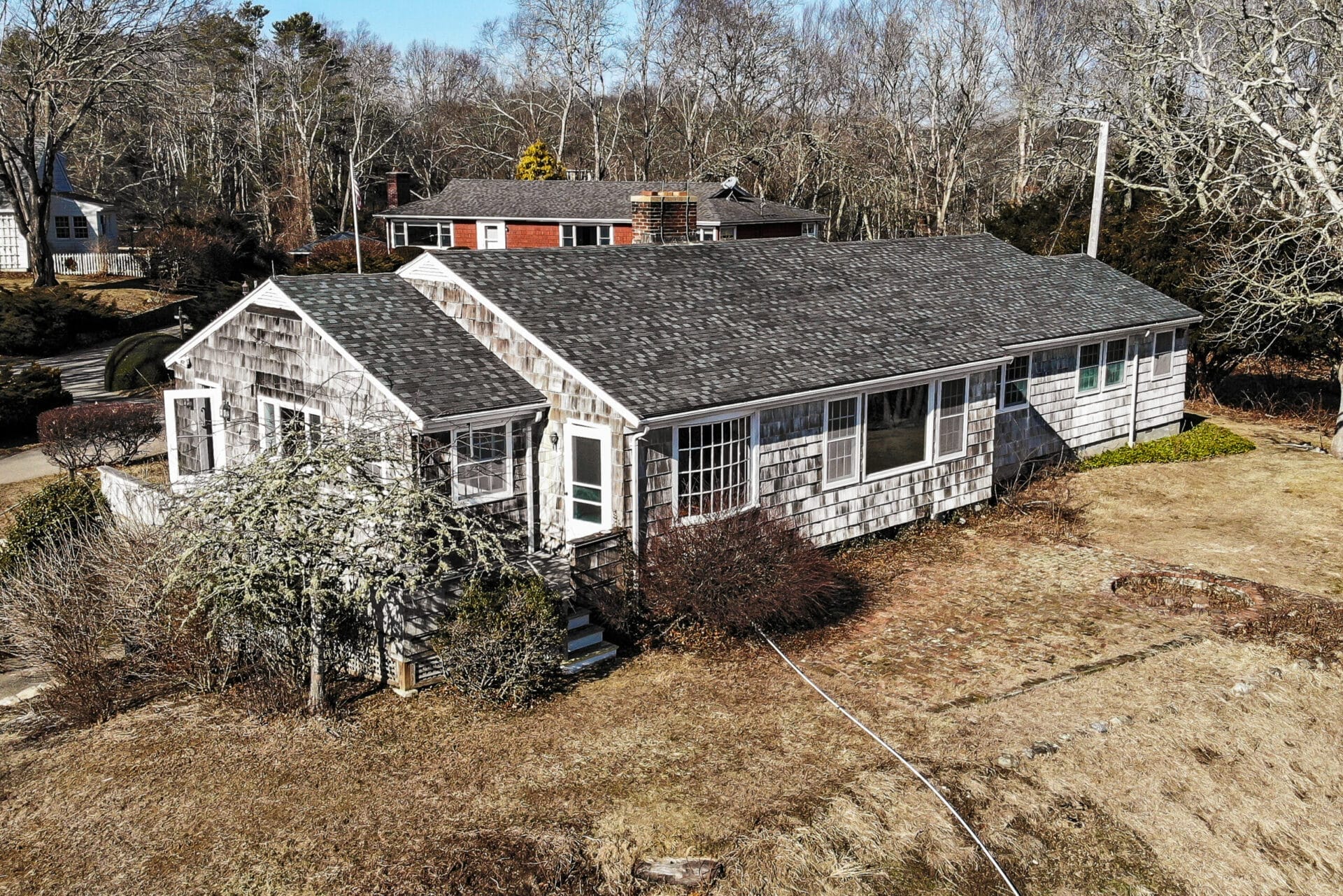 Single-story 1949 ranch house with oak tree in yard before renovation, showing original modest structure.
