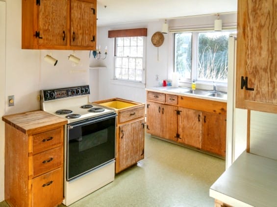 A before photo of the kitchen with pine cabinets.