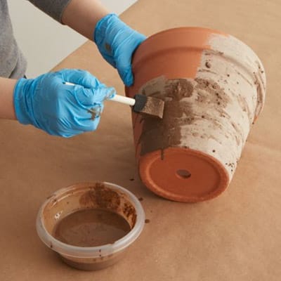 applying the garden lime and water mixture to the outside of a terra-cotta pot