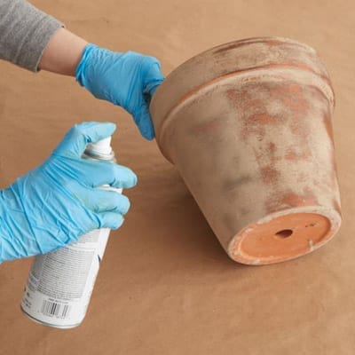 using a spray sealant to seal the mixture onto the terra-cotta pot