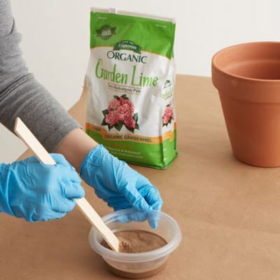 stirring the mixture of garden lime and water for a terra-cotta pot