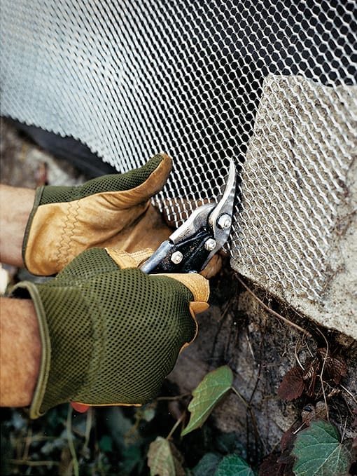A man adding mesh to an exposed wall before adding stucco.