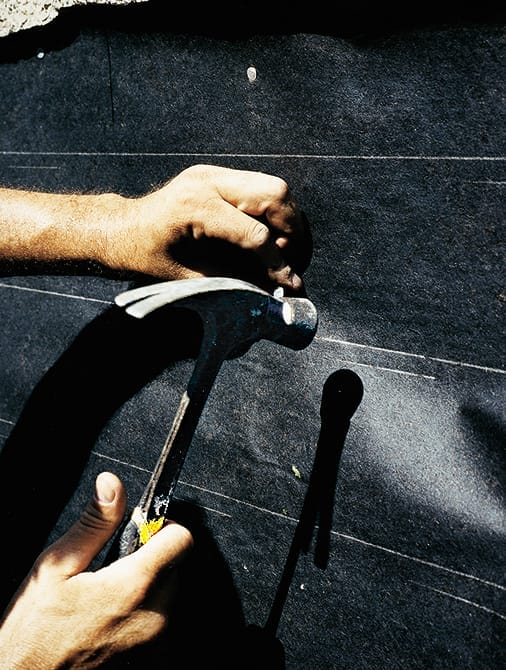 A man using builder's paper to cover an exposed wall.