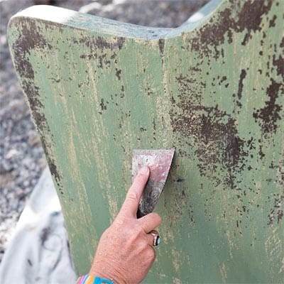Scraping and sanding the painted furniture piece.