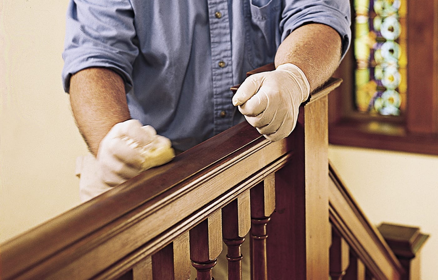 Image of a person adding wax to a stair railing to protect it after adding a new shellac finish