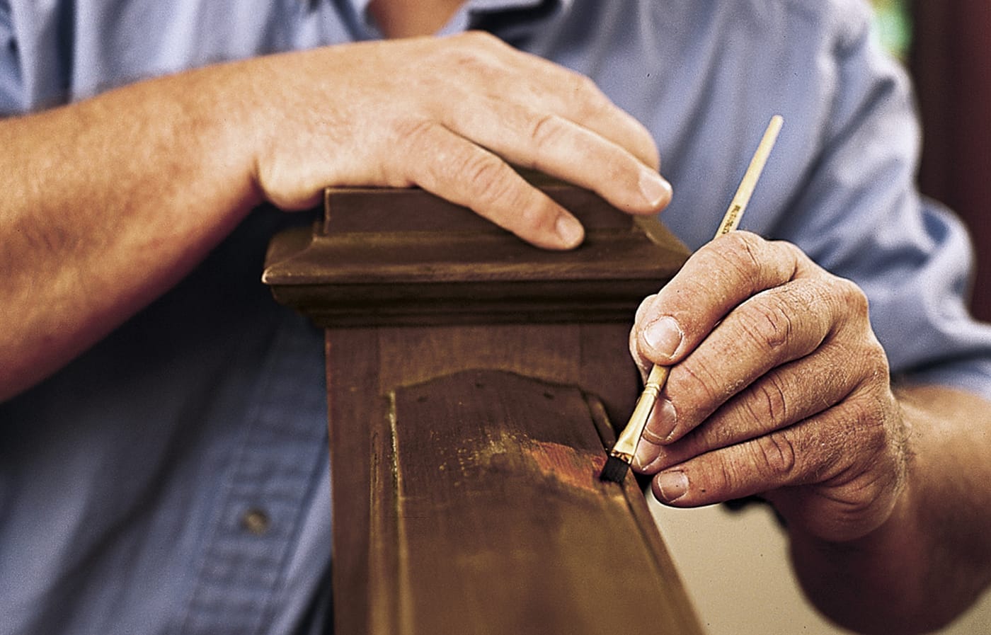 Image of a person brushing on new shellac onto a stair railing