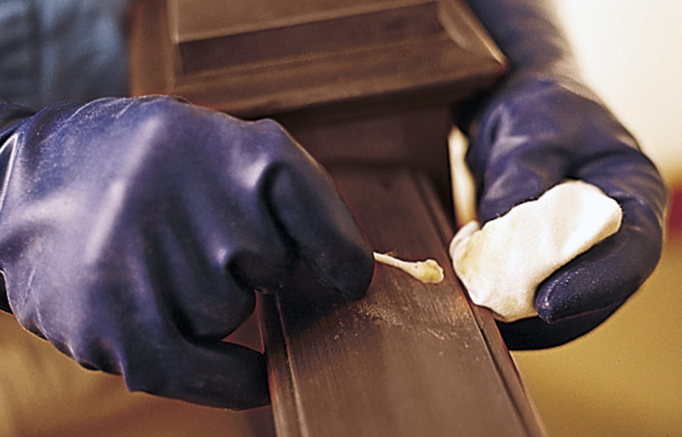 Image of a person cleaning and softening the surface of a handrail that needs to be refinished