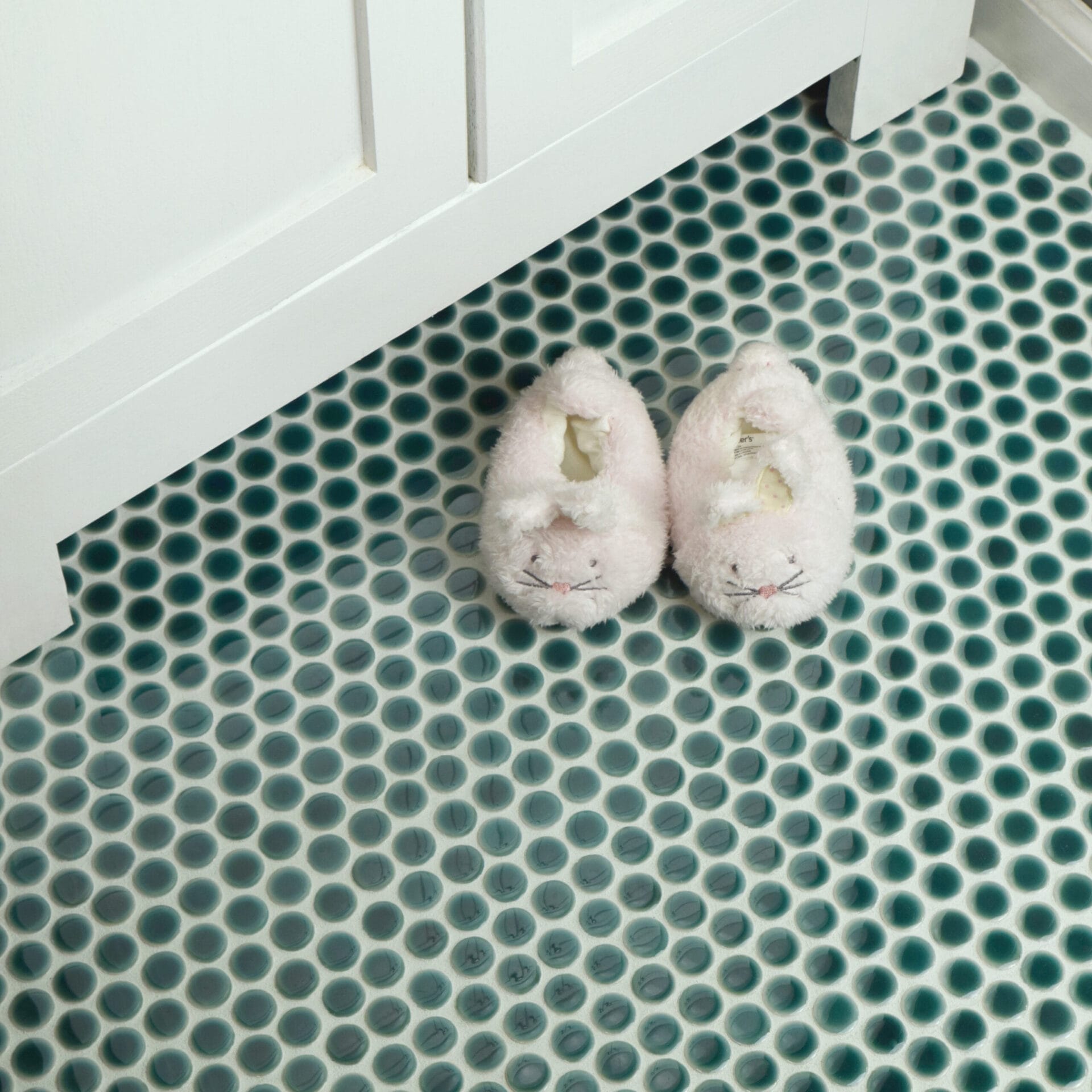 A pair of slippers on bathroom flooring.