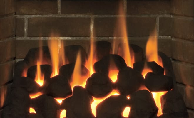 A fire growing in a fireplace.