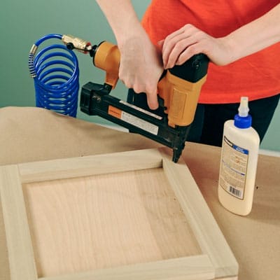 using a nail gun to attach the frame to the base of a takeout menu holder