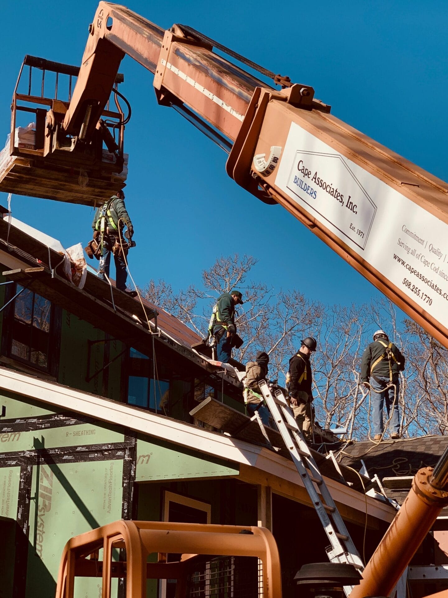 Lull raising a palette of asphalt shingles on to a roof.