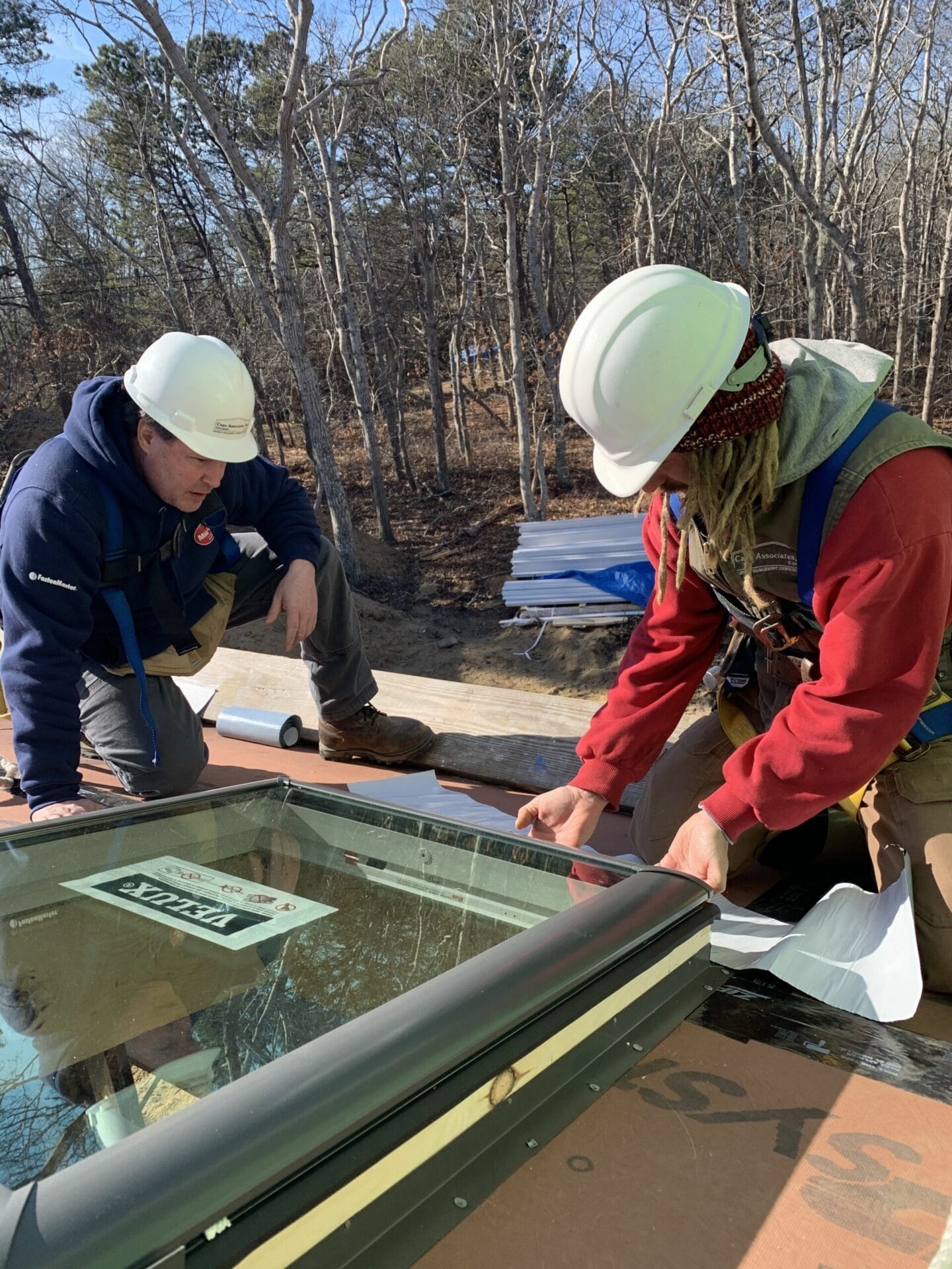 Two workers installing flashing around a skylight.