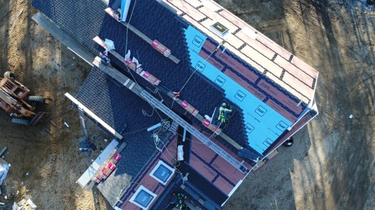 Roofers installing shingles on a house.